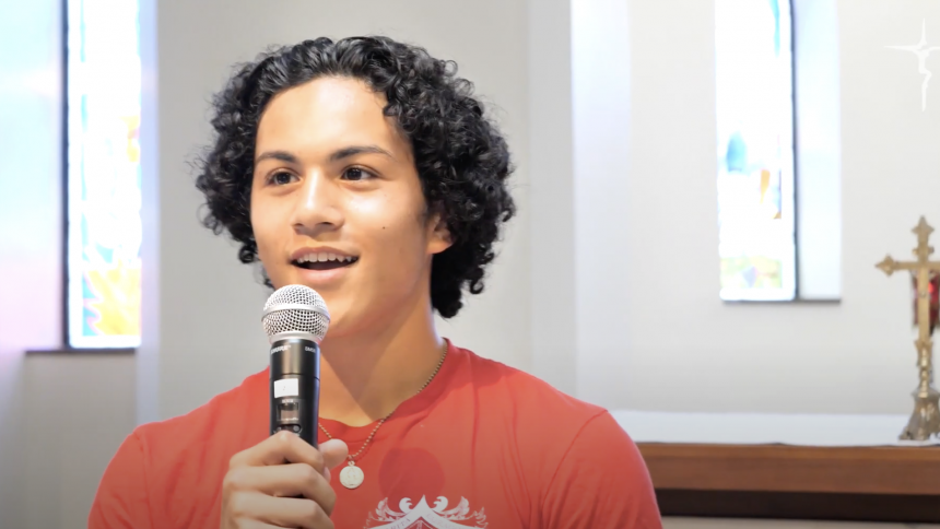 A student with curly dark hair speaks in the chapel