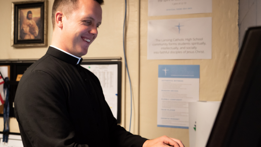 Fr. Joe Campbell is in clerics working at his computer in his office.